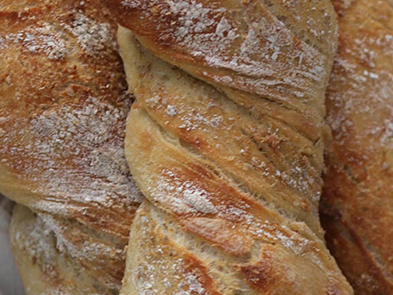 Flera nybakade bröd, fokus på baguette.